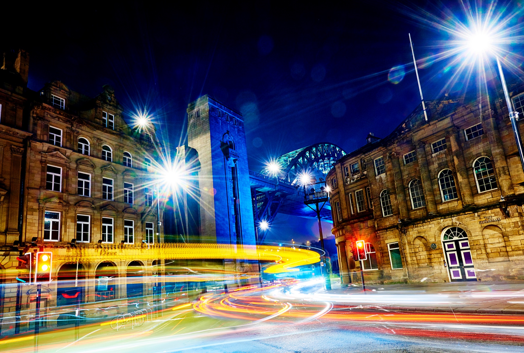Streetscape of Newcastle upon Tyne by night, with lights from traffic creating a pattern and sense of movement